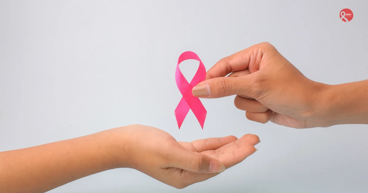 Close-up of hands exchanging a pink cancer awareness ribbon, symbolizing support, care, and commitment towards cancer prevention and treatment funding.