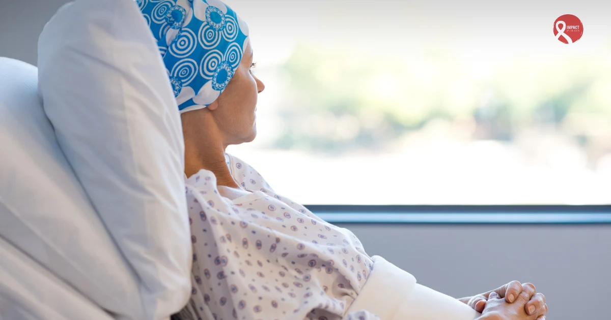 A patient wearing a headscarf sits on a hospital bed, looking out of the window, symbolizing the emotional and physical challenges faced during chemotherapy treatment.
