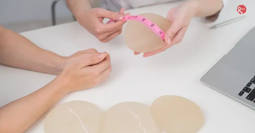 Doctor showing and measuring breast implants for post-mastectomy breast reconstruction options.