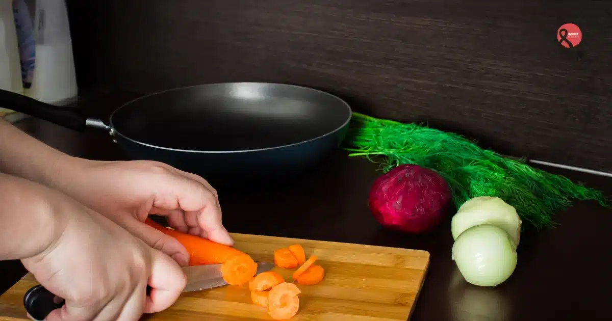 A person cutting vegetables on a chopping board beside a non-stick pan, representing everyday cooking and concerns about non-stick cookware safety.