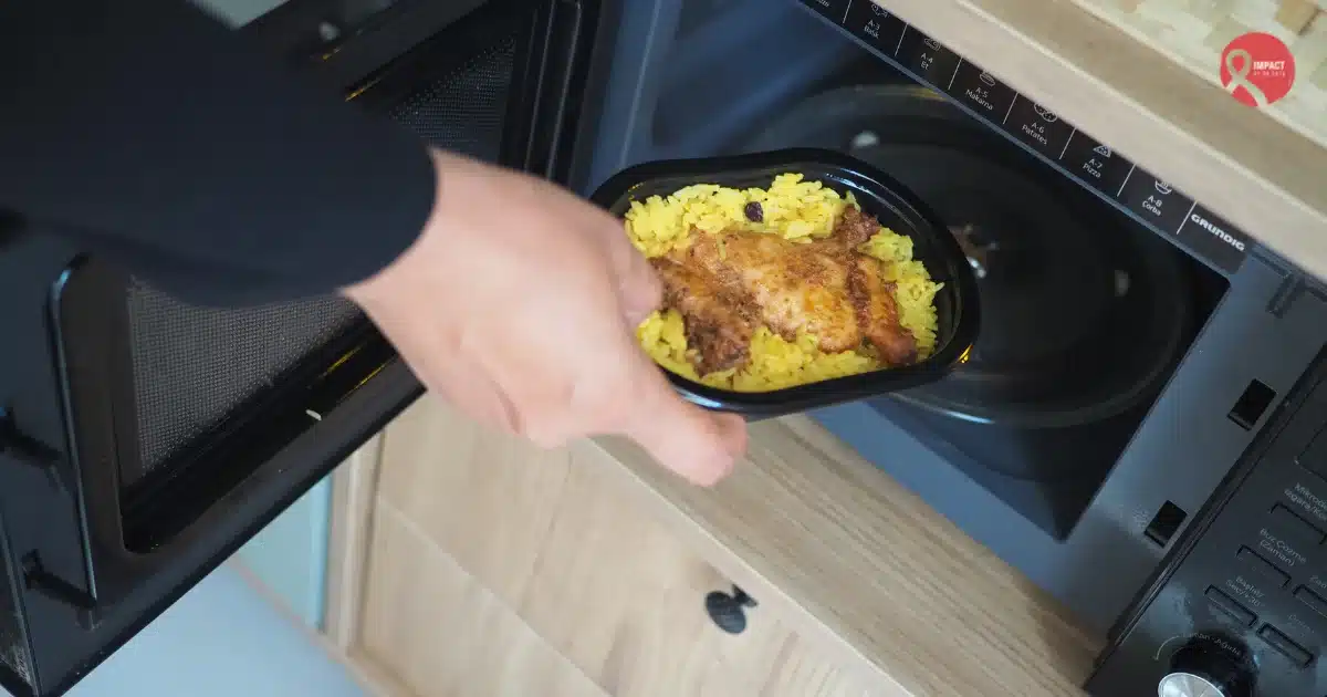 Person placing a food container in a microwave representing reheating food multiple times.